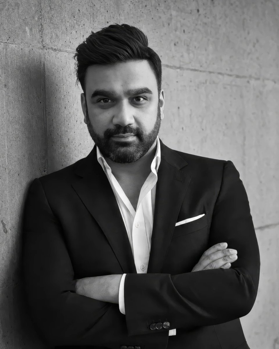 Ashish Sharma, founder of The Shaping Company, in a black jacket against a concrete wall